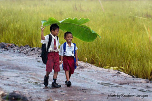 two-kids-under-a-banana-leaf-in-the-rain-indonesia name